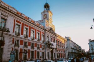View of the iconic Puerta del Sol clock tower in Madrid, Spain, during dusk.